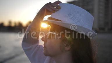 太阳眼镜的女人在日落<strong>时</strong>戴着帽子，<strong>靠近</strong>大海慢动作